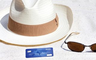 Chapéu de praia, cartão de crédito e óculos de sol