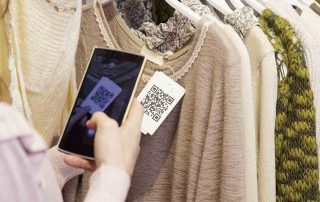 Mulher escaneando um QR Code com seu celular de uma etiqueta em uma blusa