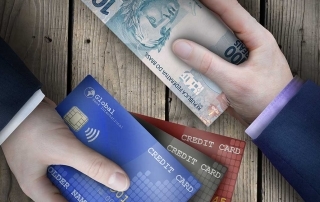 Mão entregando dinheiro e outra entregando cartão de crédito em autorização parcial de pagamento