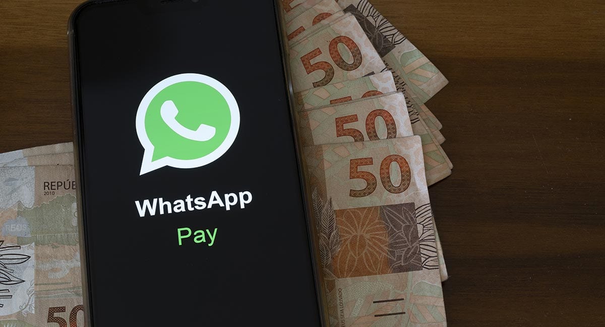 Celular com logo WhatsApp Pay e cédulas de reais