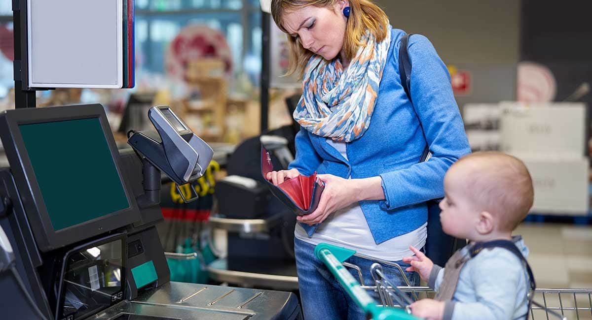 Mulher e bebê pagando no self-checkout